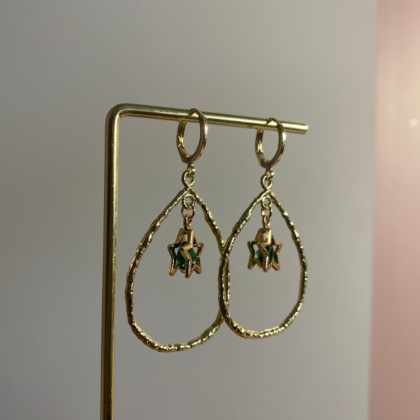 Een foto van de Estelle oorbellen van lellebel sieraden. 14k vergulde oorbel met ster en steentje in open ring, feestelijke lengte van 4 cm.