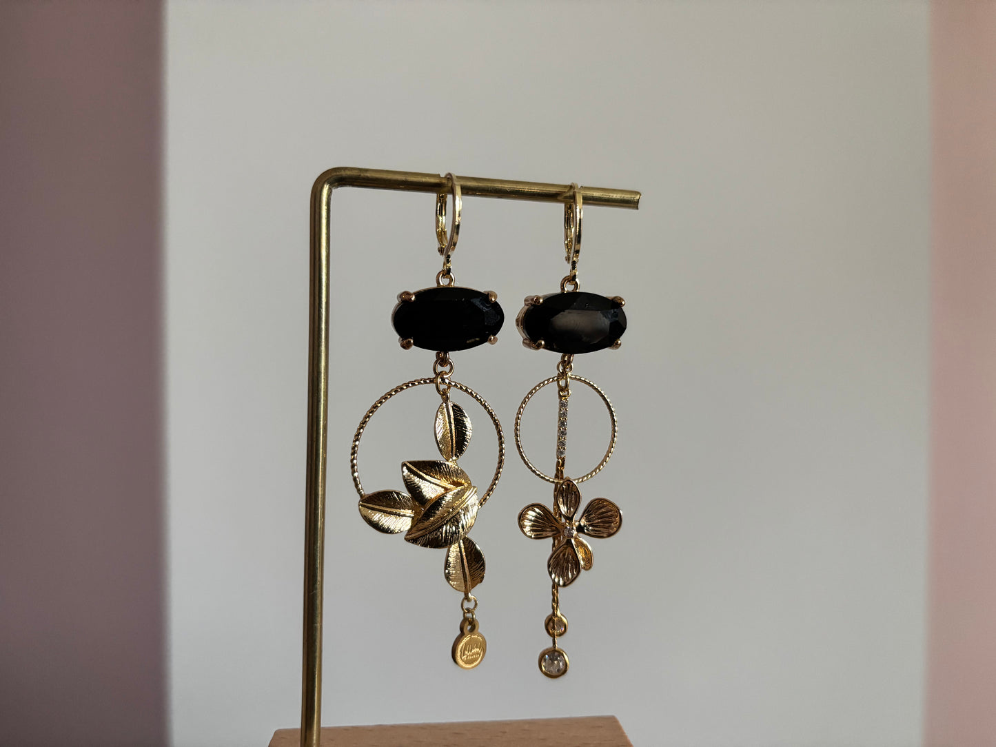 Asymmetrische 14K vergulde oorbellen met glazen bedels en gouden bloem- en bladmotieven.