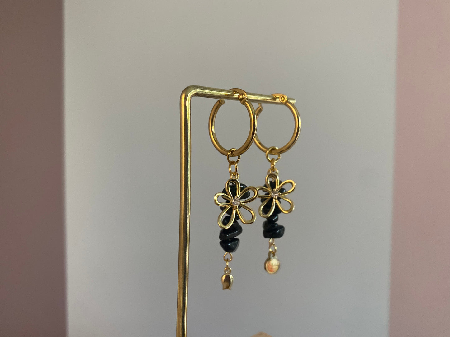 Handgemaakte vergulde gouden oorbellen bestaande uit RVS hoops met daaraan zwarte natuurstenen met een 14K vergulde bloembedel met ingelegde zirkonia.