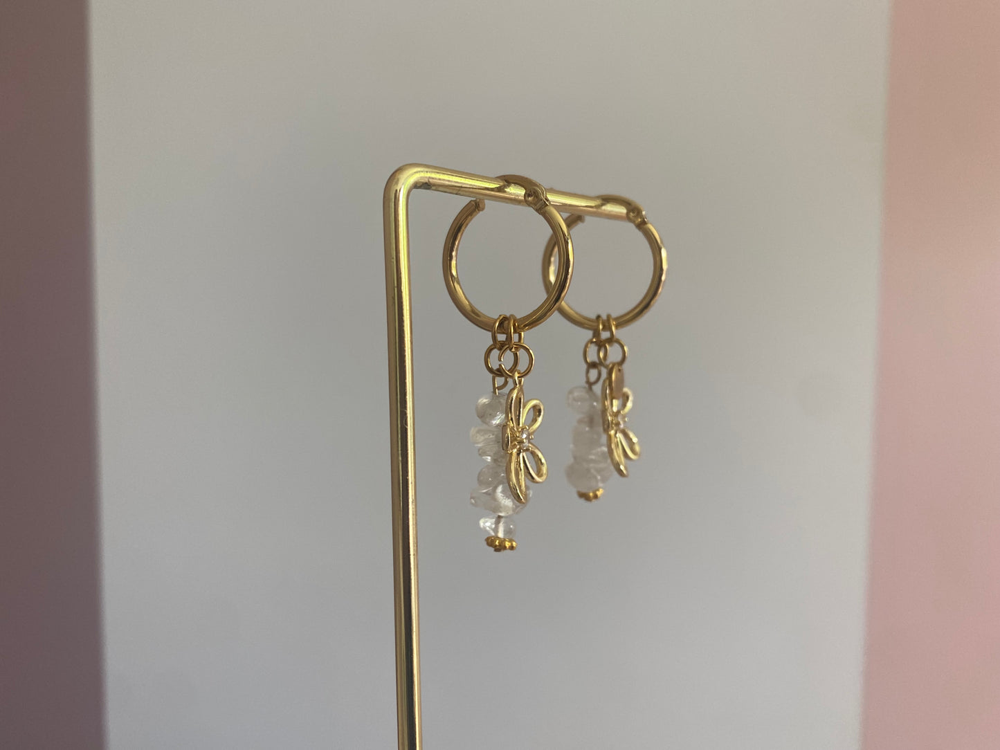 foto van de zijkant van andgemaakte vergulde gouden oorbellen bestaande uit RVS hoops met daaraan witte en zachtroze natuurstenen met een 14K vergulde bloembedel met ingelegde zirkonia.