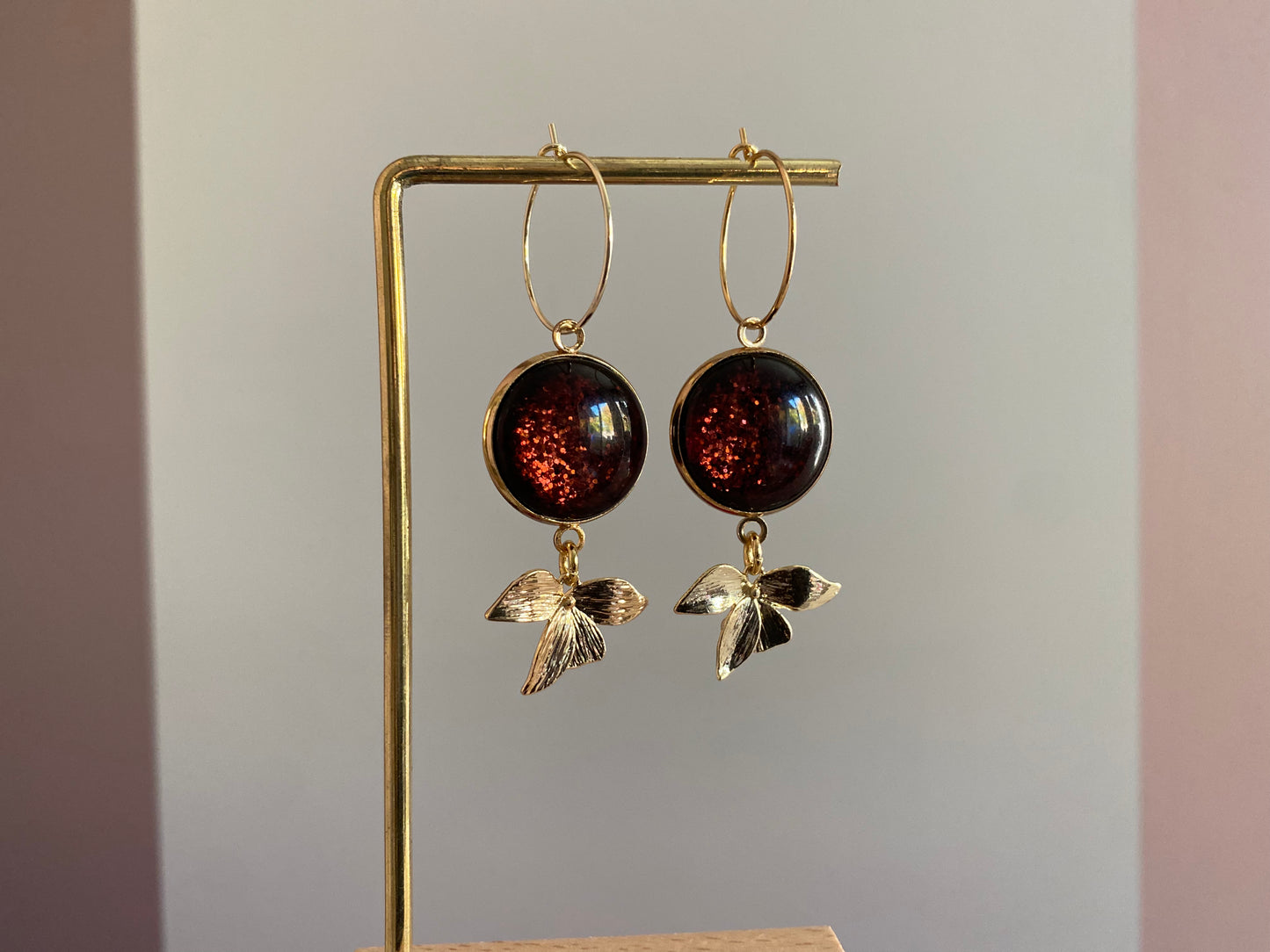 Symmetrische 14k vergulde oorbellen met roodbruine glitter cabochon, minimalistische ring en bladaccent — feestelijke en elegante uitstralin