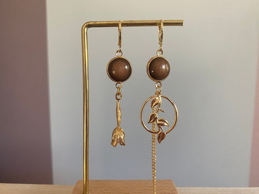 Asymmetrisch mismatch paar met een donkerbruine cabochon en 14k vergulde Roos, rechts donkerbruine cabochon, blad bedel en verguld kwastje