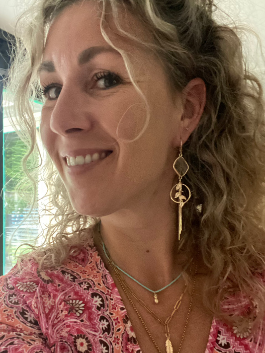 asymmetrisch paar oorbellen, twee verschillende oorbellen. Éen met een 14k vergulde roos andere met een bedel met bladeren ook 14k. Doorzichtige glazen bedel erboven