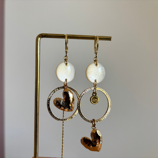 Asymmetrische 14k vergulde oorbellen Ivy met witte parelmoer cabochon, gehamerde ringen, hartvormige bedel en kwastje, circa 7 cm lang