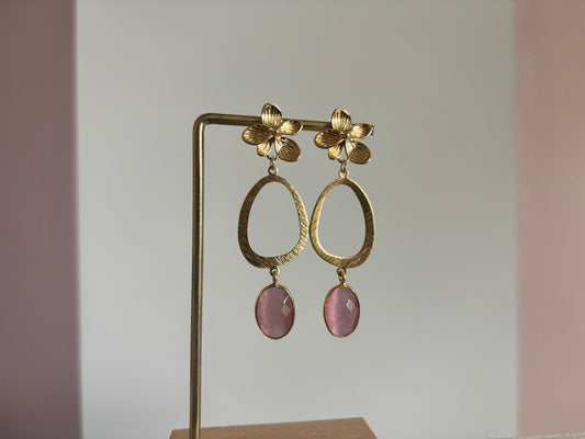 14k vergulde oorbellen 'Julia' van Lellebel op een gouden standaard. De set bestaat uit een goudkleurige bloem met daaronder een grote ovale ring en een kleine, druppelvormige zachtroze steen.