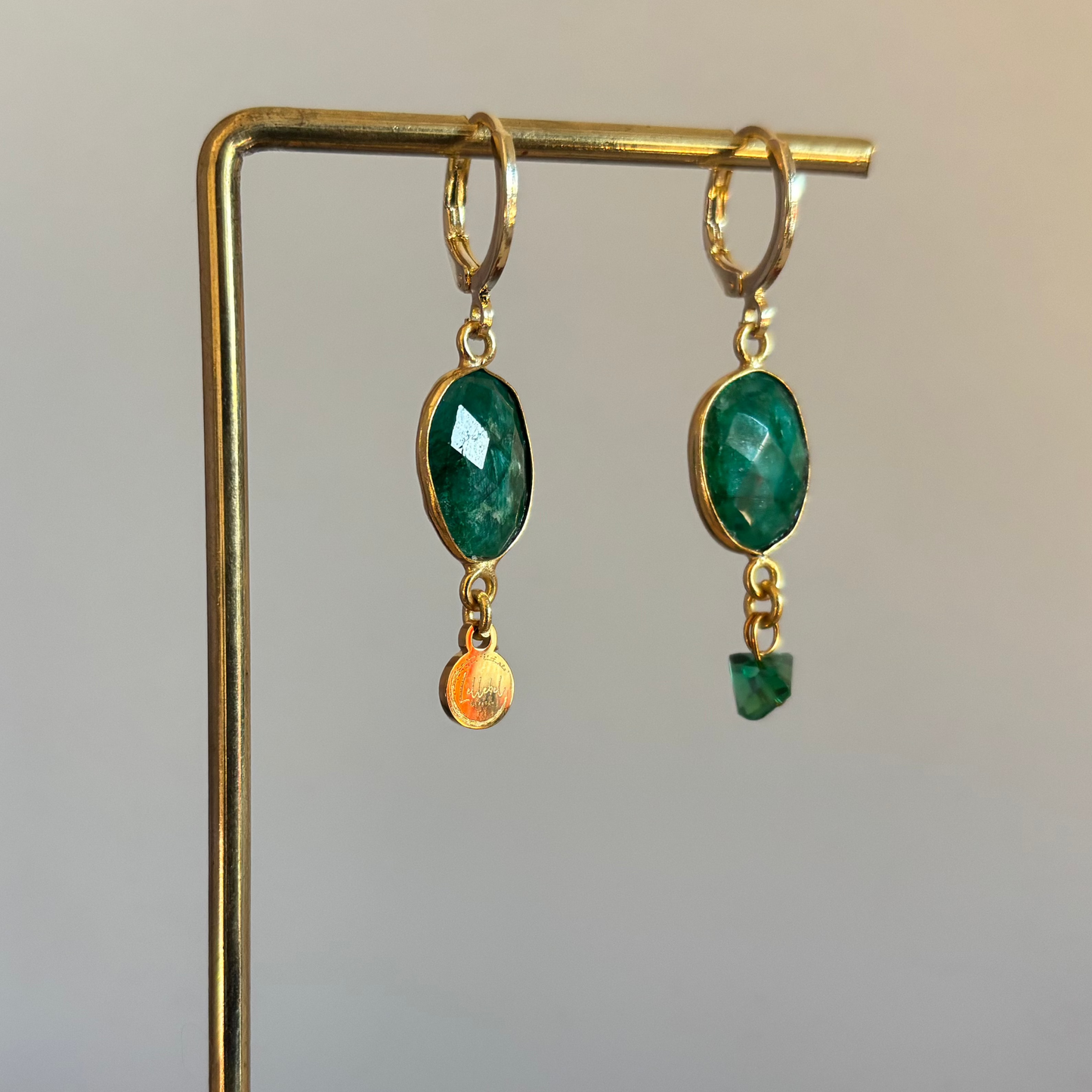 Minimalistische 14k vergulde groene oorbellen met merktag en groen steentje."