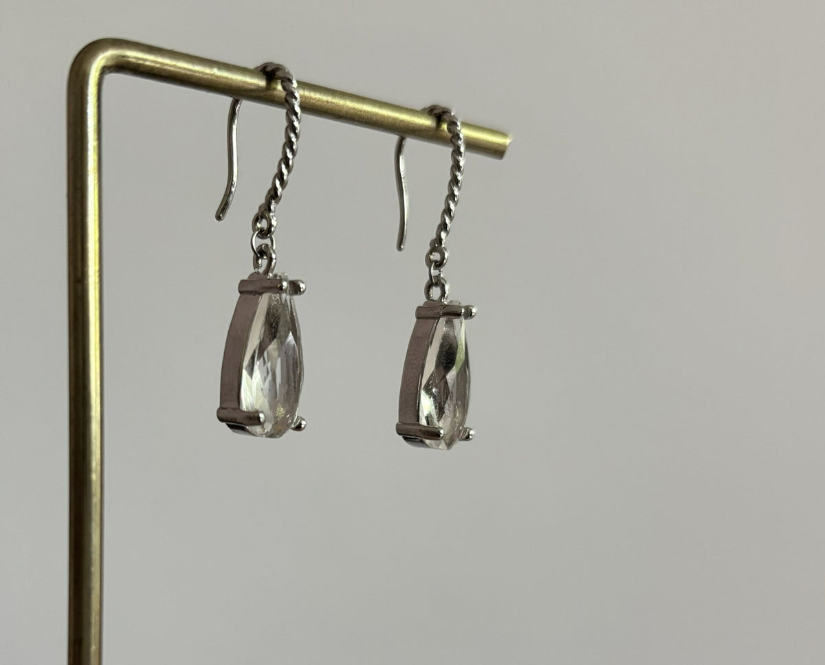 Kiek Clear oorbellen van verguld zilver met gedraaide oorhaken en een hangende, traanvormige heldere gefacetteerde glassteen.