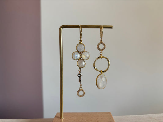 asymmetrisch paar met maanstenen, zirkonia ingelegde bedels en een 14k verguld sleuteltje