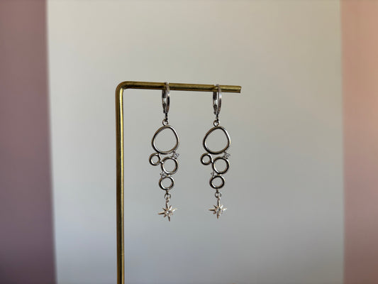 Minimalistische bedel met meerdere cirkeltjes met zirkonia en een klein zirkonia sterretje, circa 4 cm lang.