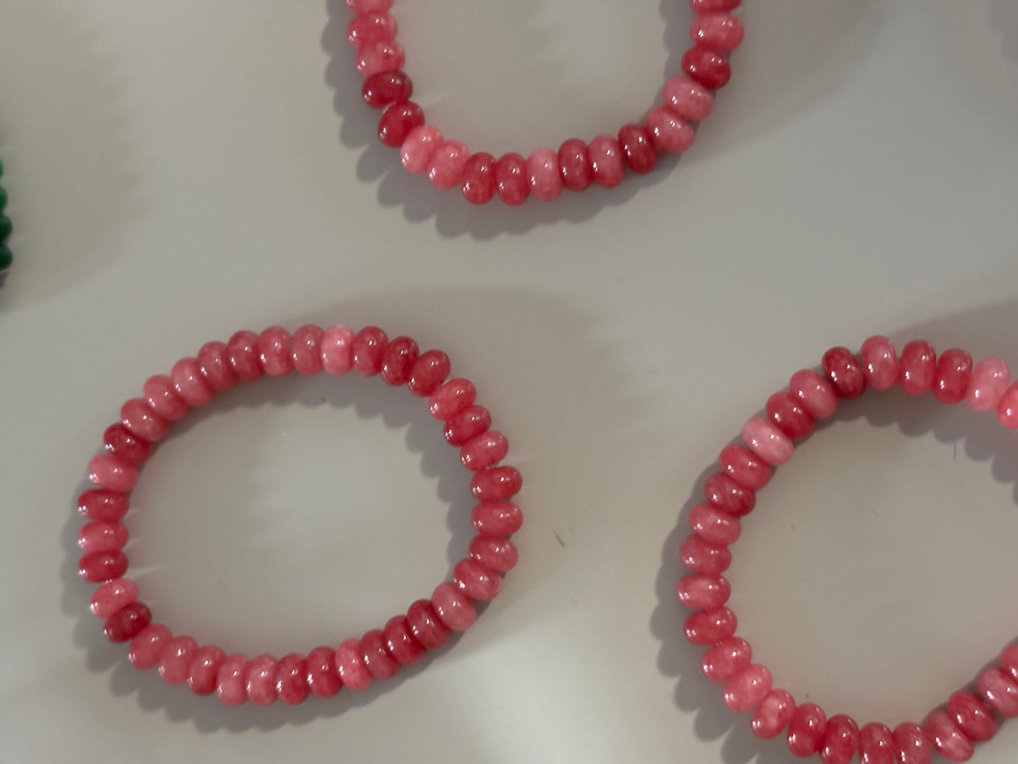 Feline armband met natuurstenen kralen in magenta, groen of zachtroze, afgewerkt met roestvrijstalen kettinkje, verstelbaar door elastiek