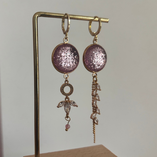 Asymmetrische 14k vergulde oorbellen 'Nina' met glinsterende roze ronde stenen en hangers van heldere kristallen op een gouden standaard.