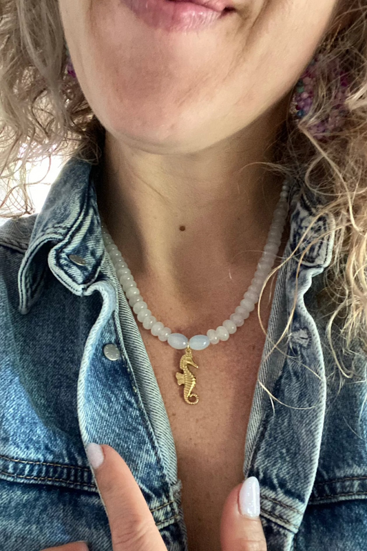 Model draagt Witte natuurstenen ketting met 14K verguld zeepaardje als bedel