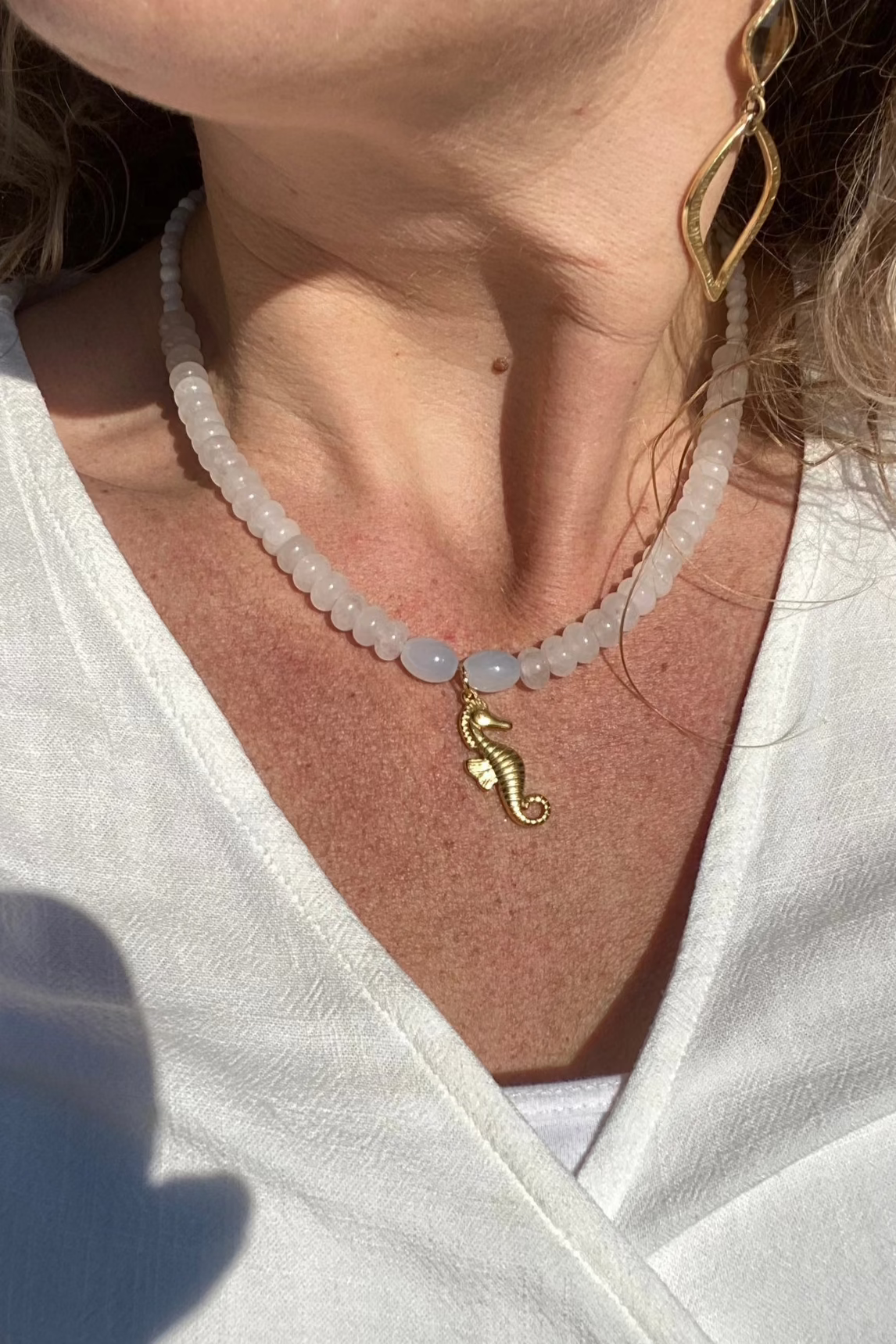 Model met Witte natuurstenen ketting met 14K verguld zeepaardje als bedel