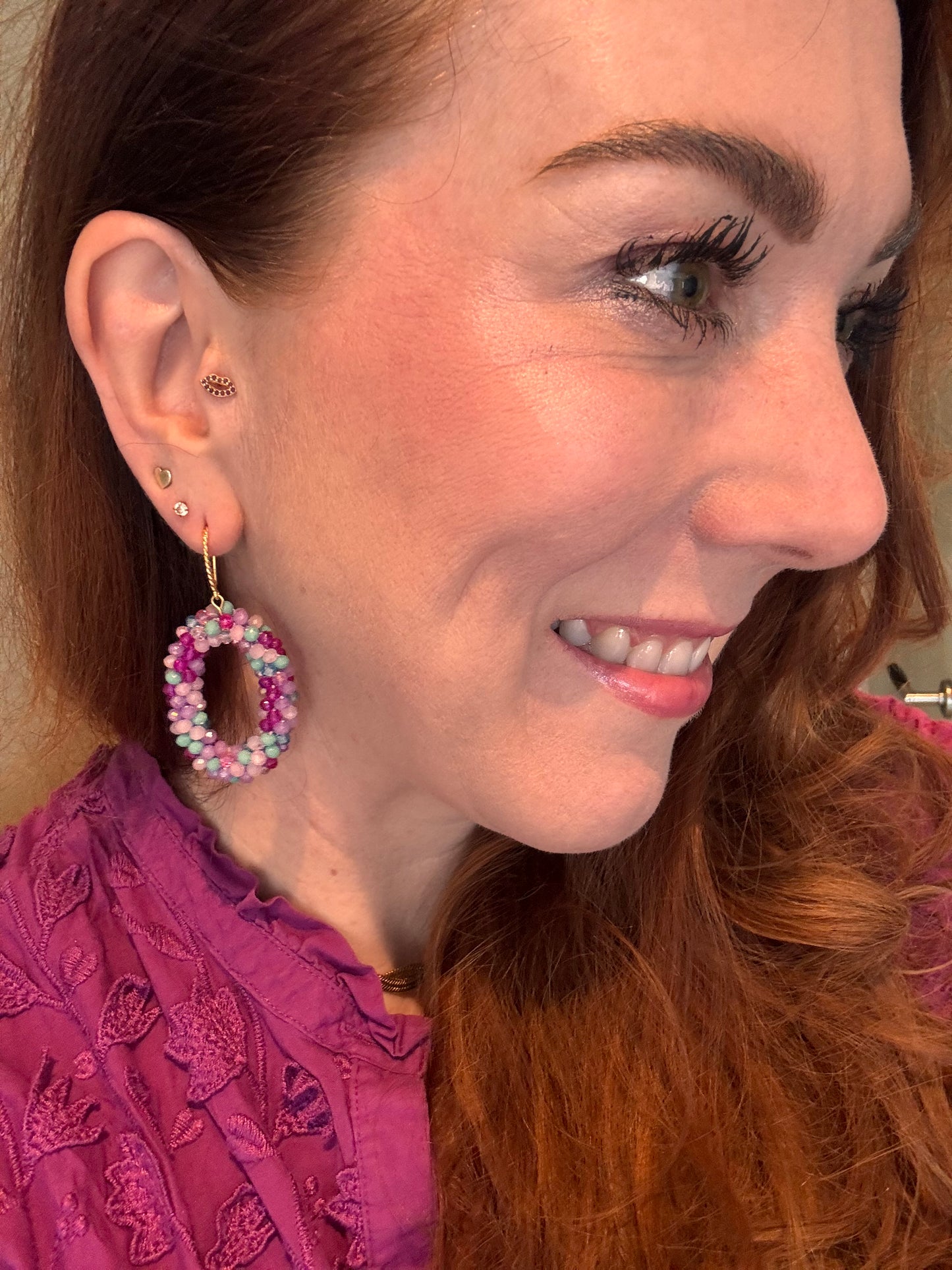 Model met statement oorbellen met kraaltjes in Lila, paars, zachtroze en zeeblauw aan een 14k verguld haakje