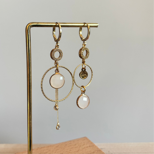 Een productfoto van het ongelijke paar Lellebel Oorbellen "Sandra", met zirkonia hangers en witte glasbedels.