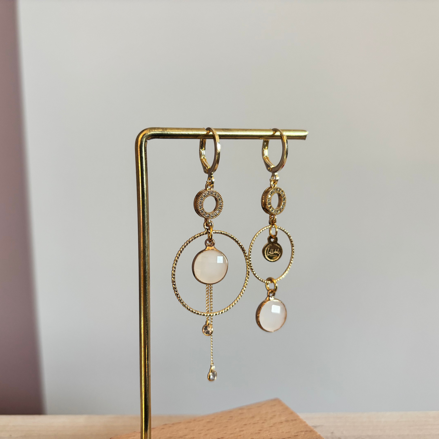 Een productfoto van het ongelijke paar Lellebel Oorbellen "Sandra", met zirkonia hangers en witte glasbedels.