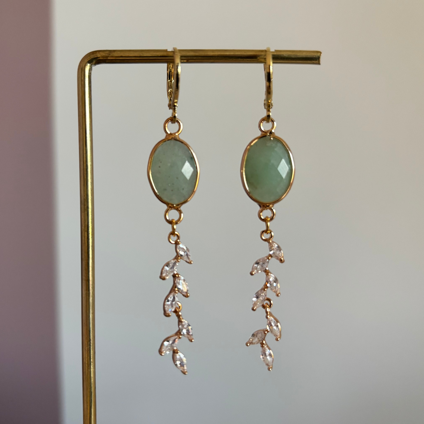 Soof oorbellen van 14k goud verguld met een ovale groene steen en een hanger van zirkonia steentjes in de vorm van een takje.