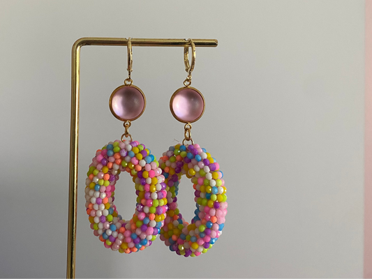 Statementoorbel van neonkleurige kraaltjes aan een lichtroze cabochon steker.