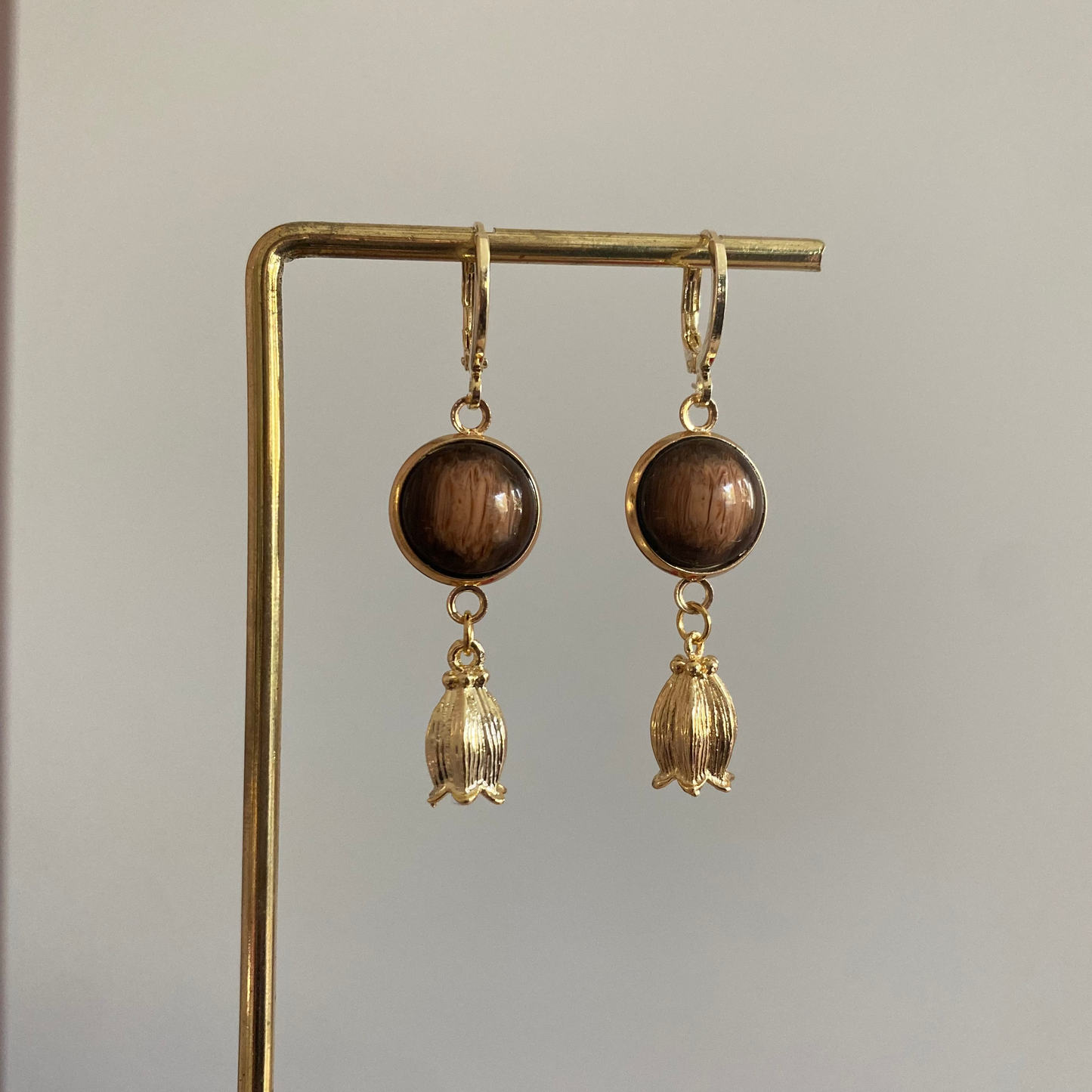 Korte oorbel met donkerbruine cabochon en een 14k vergulde tulpbedel eronde