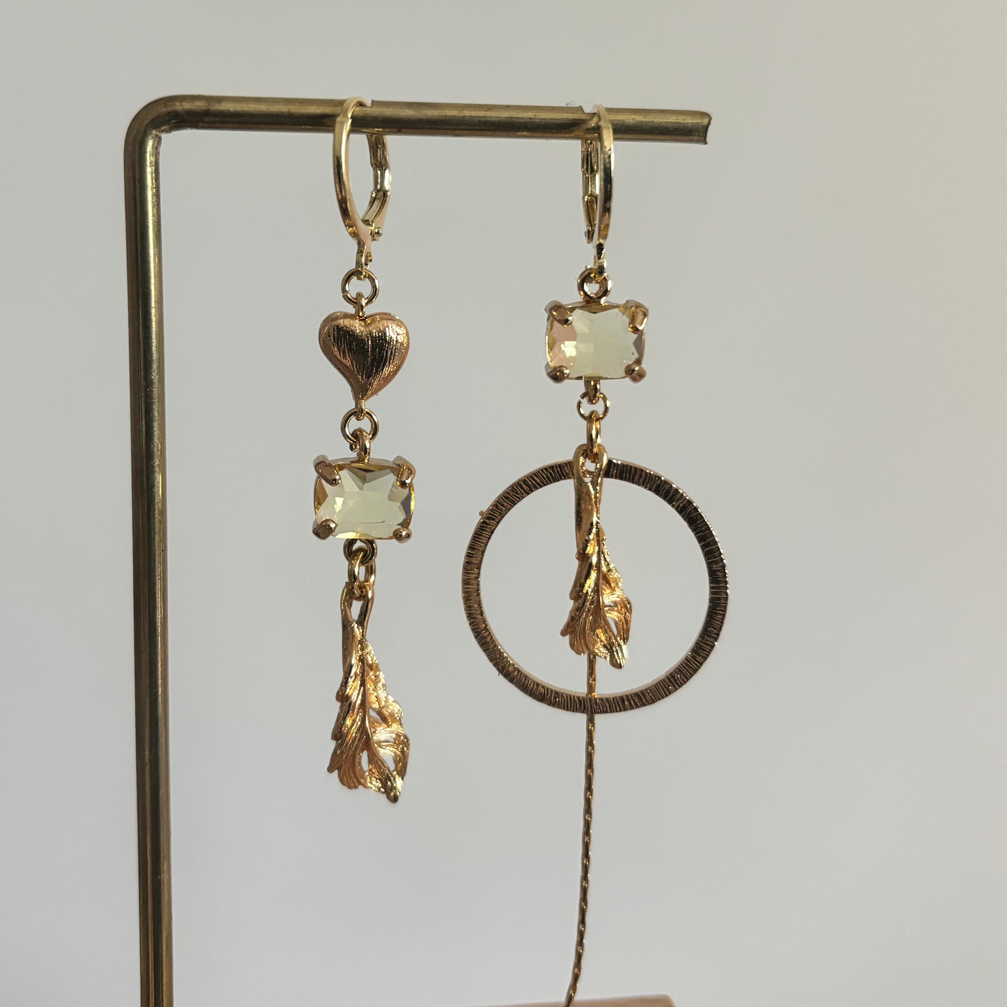Veertje mismatch oorbellen goud met veer, hartje, glasbedel en kwastje, asymmetrisch design