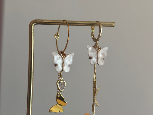 Asymmetrisch paar met 14K vergulde vlinderstreng, Shell vlinders en een mini glazen hartjesbedel, aan een 14K gouden oorringetje