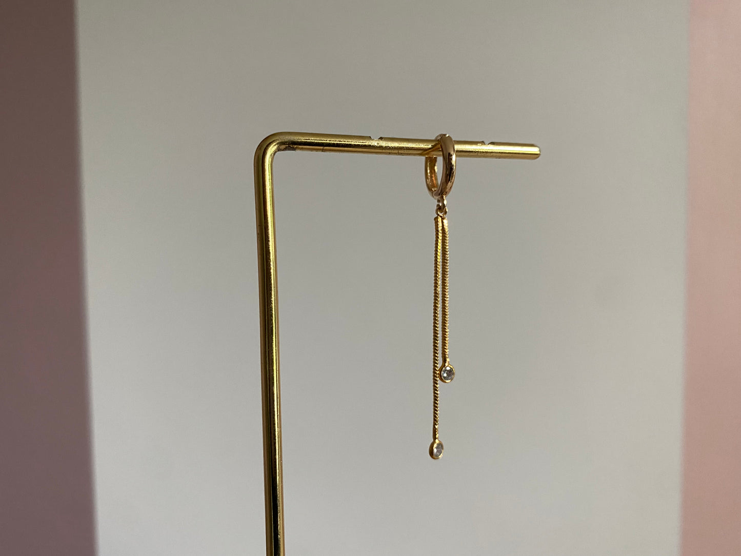 Handgemaakte 14K vergulde oorbel met daaraan een 14K vergulden gouden strengetje met zirkonia bedels.