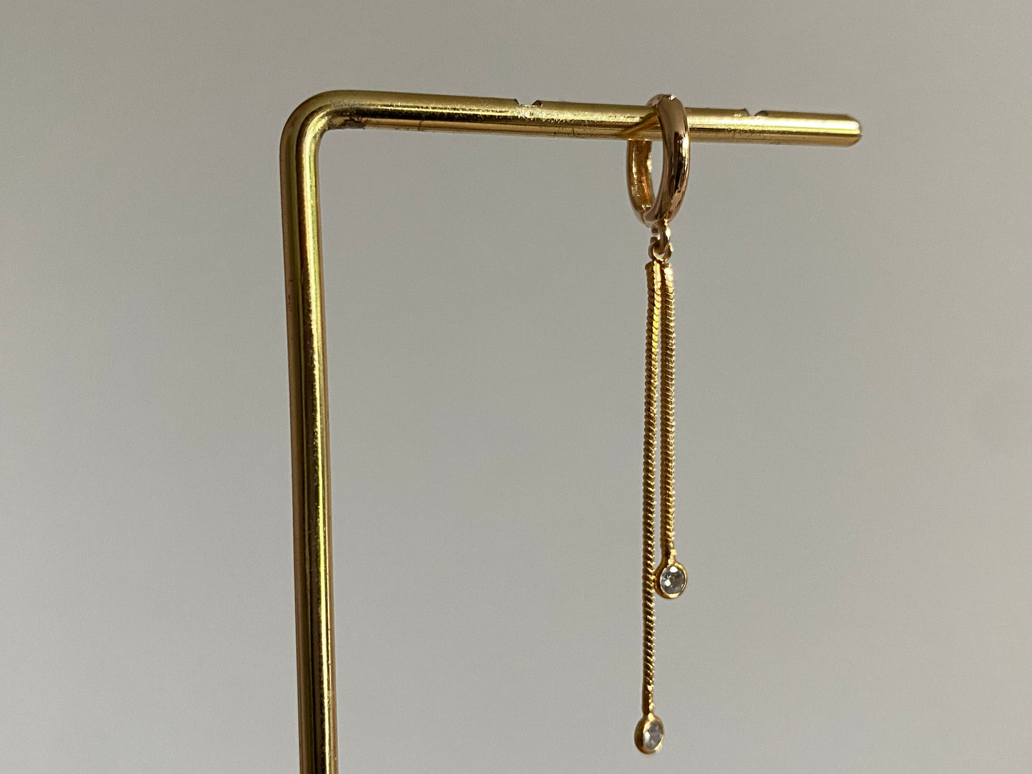 Handgemaakte 14K vergulde oorbel met daaraan een 14K vergulden gouden strengetje met zirkonia bedels.
