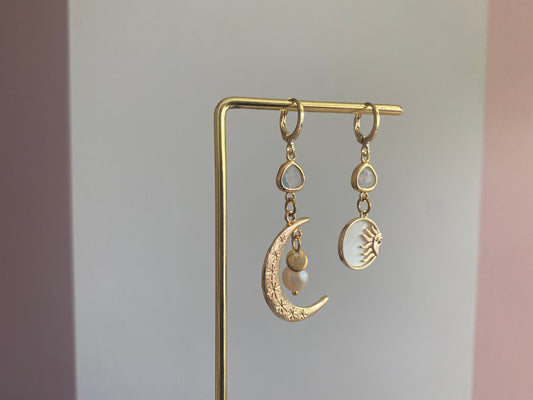 Asymmetrische oorbellen met een 14K gouden vergulde maan, glasbedel en een parelmoerhanger met daarin een 14K vergulde zon en zirkonia.