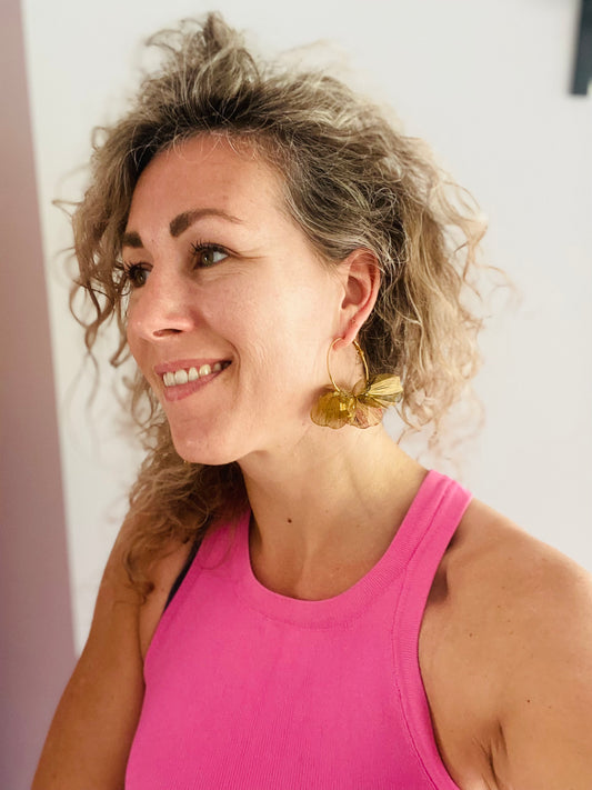 Model met statement bloem oorbel gemaakt van verguld RVS.