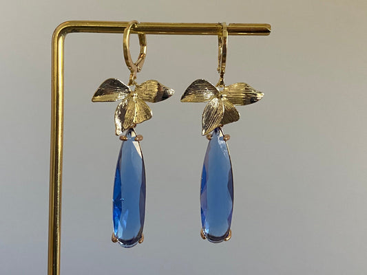14K vergulde en handgemaakte oorbel met vergulde oorringetjes, blaadjes en een langwerpige blauwe rechthoekige glasbedel. 