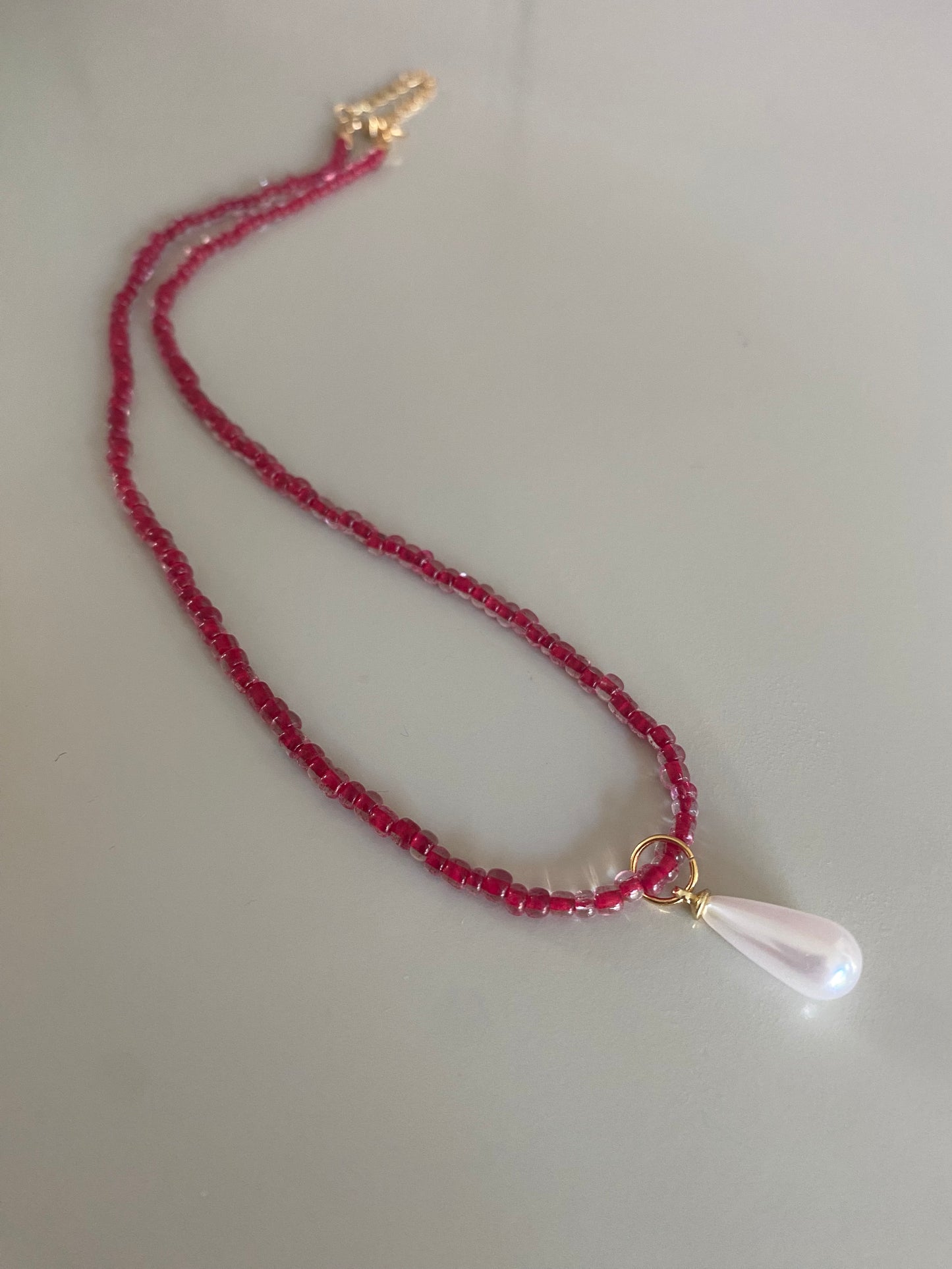 Rode glaskralen of rijstkralen ketting met een parel bedel 