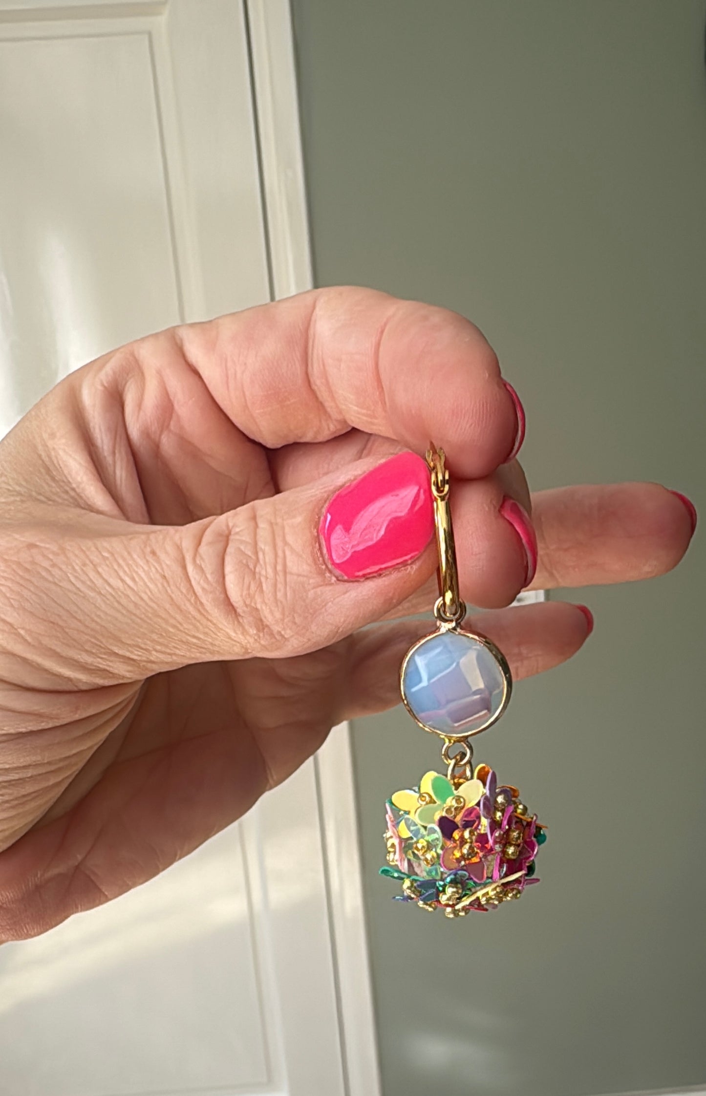 Presenteertfoto van Bolletjes oorbel van holografische bloemetjes in regenboog kleuren, een parelmoeren glasbedel en RVS oorringen 