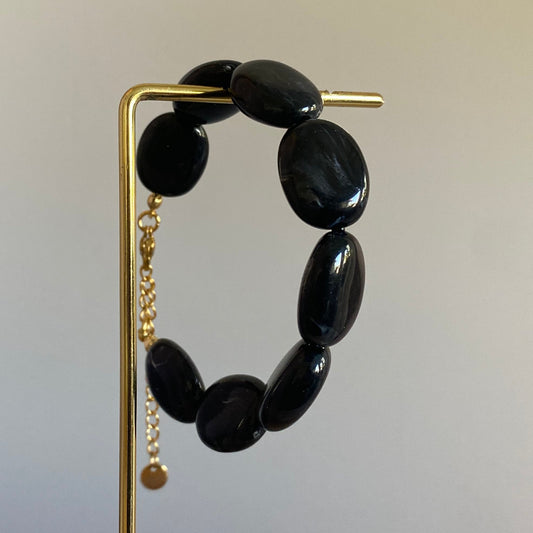 Handgemaakte en verstelbare armband in zwarte acryl kralen, afgewerkt met een hoogwaardige stainless steel sluiting 