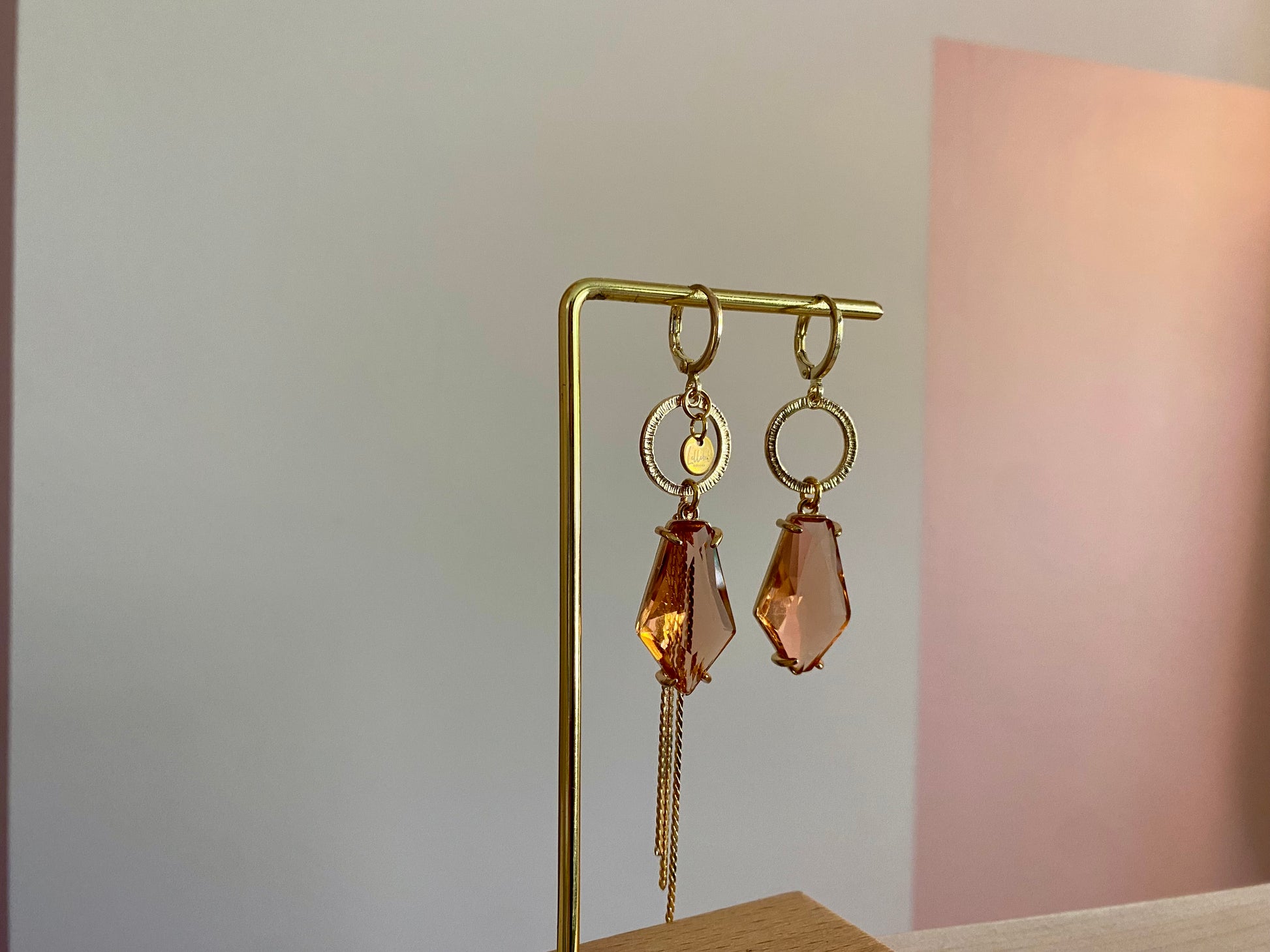 Asymmetrische oorbellen met gehamerde gouden ring, klein merk logo, roest oranje glasbedel in de vorm van een hexagon en gouden streng 