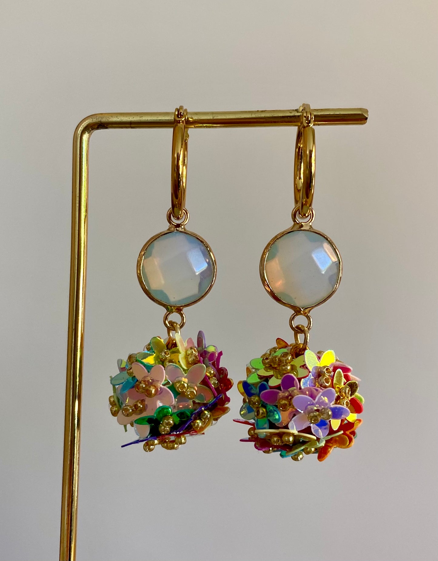 Bolletjes oorbel van holografische bloemetjes in regenboog kleuren, een parelmoeren glasbedel en RVS oorringen 