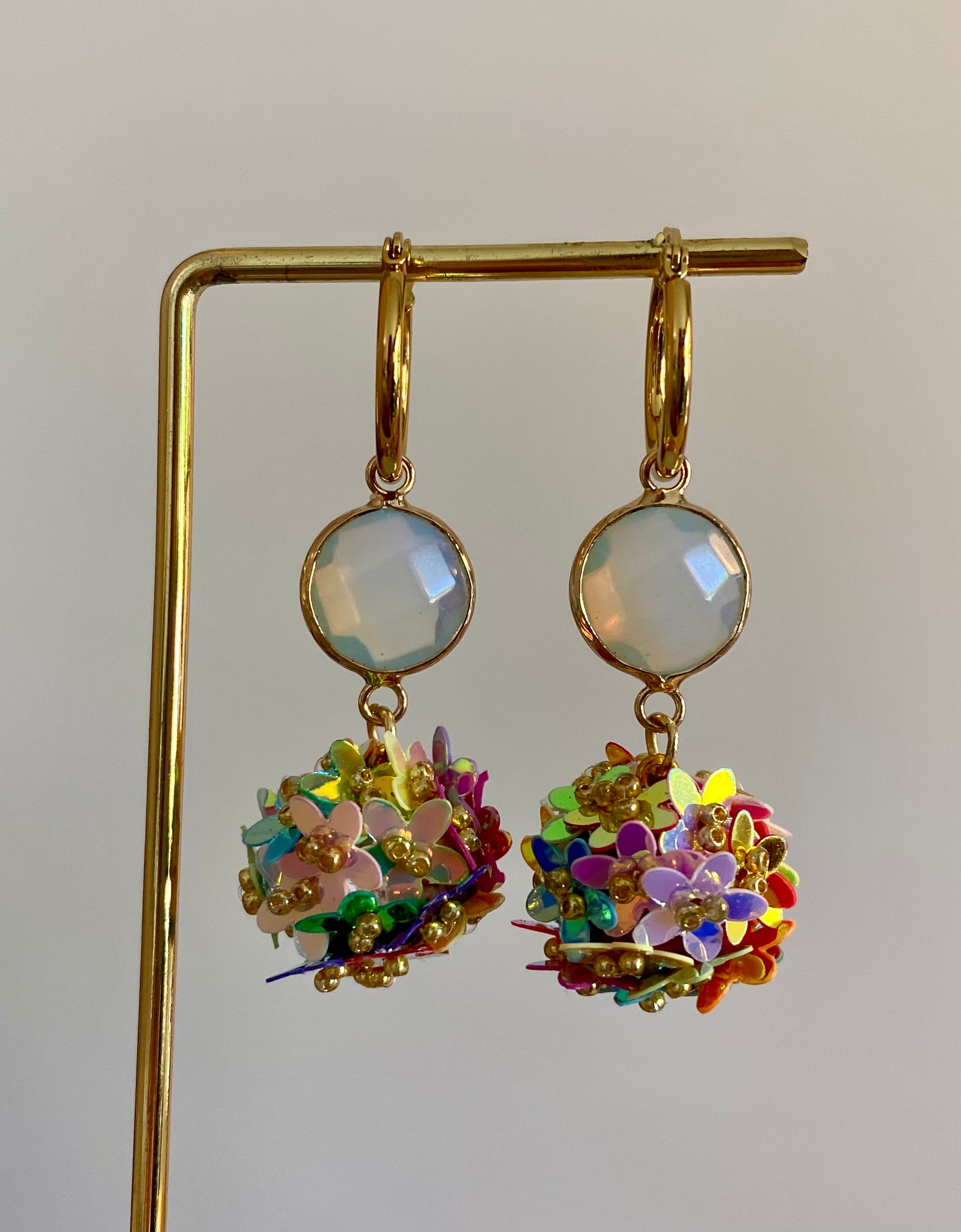 Bolletjes oorbel van holografische bloemetjes in regenboog kleuren, een parelmoeren glasbedel en RVS oorringen 