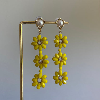 Handgemaakte oorbel met 3 gele  bloemen onder elkaar van glanzende kralen en een 14K vergulde steker met parel in de vorm van een bloem.