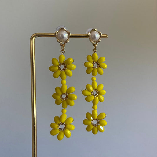 Handgemaakte oorbel met 3 gele  bloemen onder elkaar van glanzende kralen en een 14K vergulde steker met parel in de vorm van een bloem.