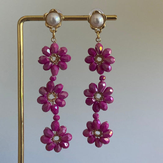 Handgemaakte oorbel met 3 roze  bloemen onder elkaar van glanzende kralen en een 14K vergulde steker met parel in de vorm van een bloem.