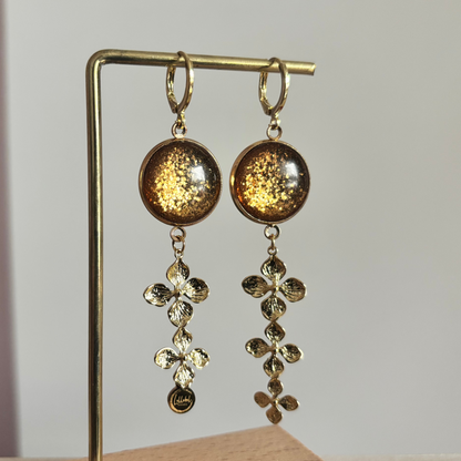 14k vergulde oorbellen 'Amber' met warmbruine glitterstenen en hangers van drie gouden bloemetjes.
