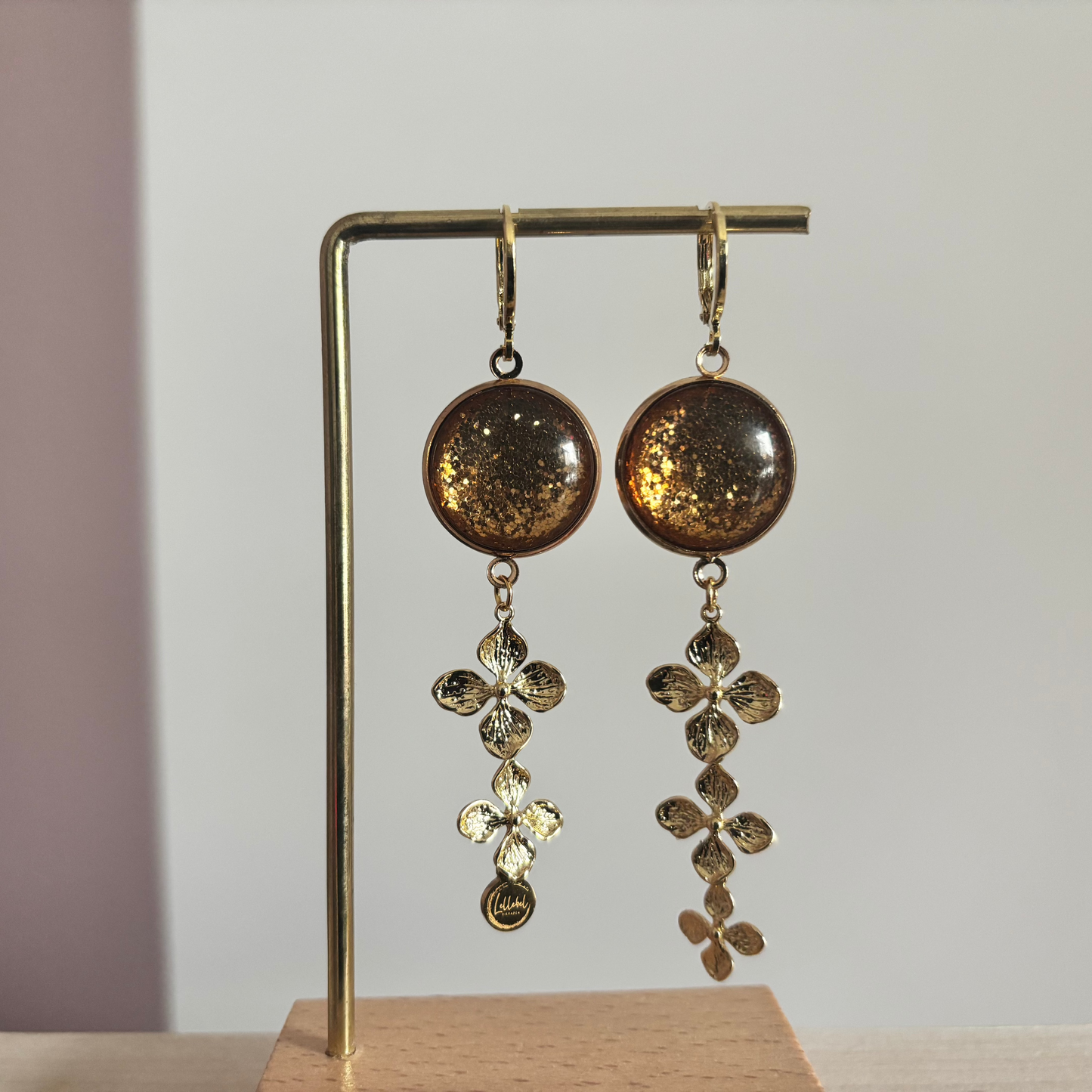 14k vergulde oorbellen 'Amber' met warmbruine glitterstenen en hangers van drie gouden bloemetjes.