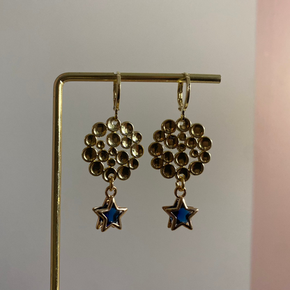 Een foto van de oorbellen "Annabelle"; Een 14k vergulde oorbel met ster en steentje, gecombineerd met een bubbelende hanger, lengte 4 cm.