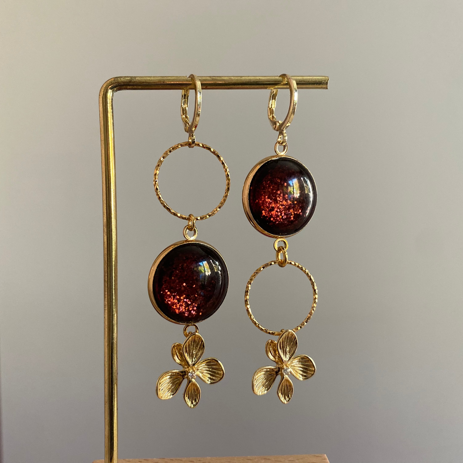 Asymmetrische 14k vergulde oorbellen met roodbruine glitter cabochon en zwarte glassteen — feestelijke variant van het populaire model Annick