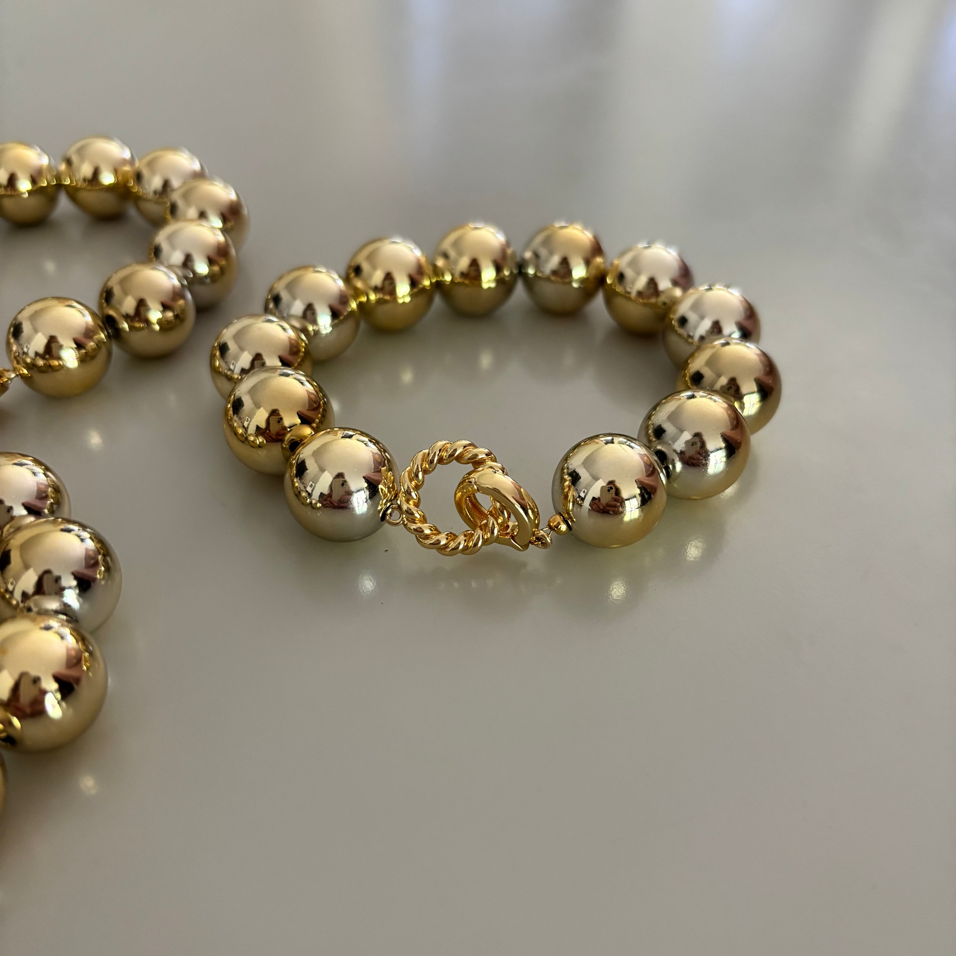 Gouden chunky kralenarmband met grote glimmende 16 mm CCB-kralen en een bewerkte ronde connector-sluiting.