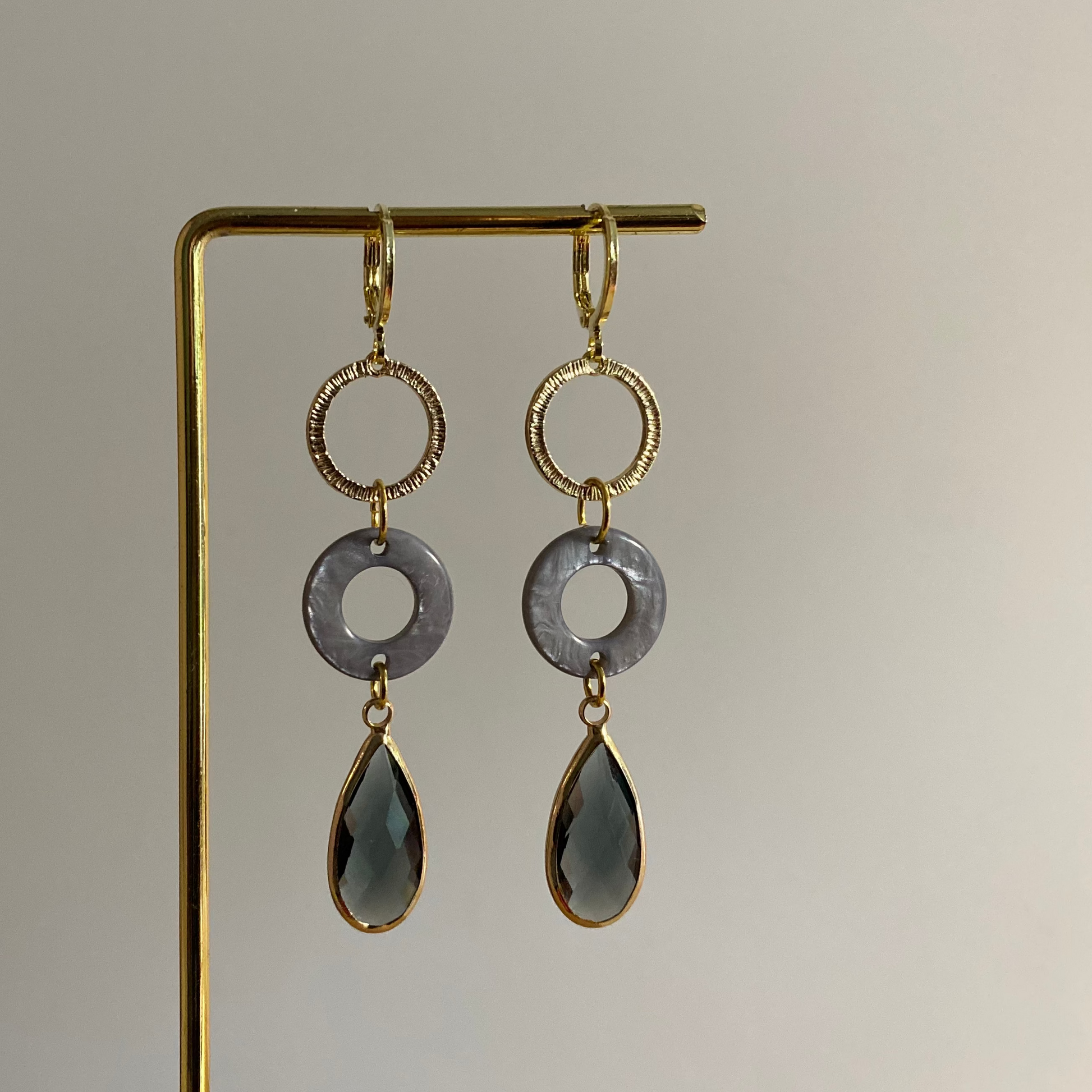 14k vergulde Barbara oorbellen met gehamerde ring, blauwe cabochon en grijze druppelvormige glasbedel.