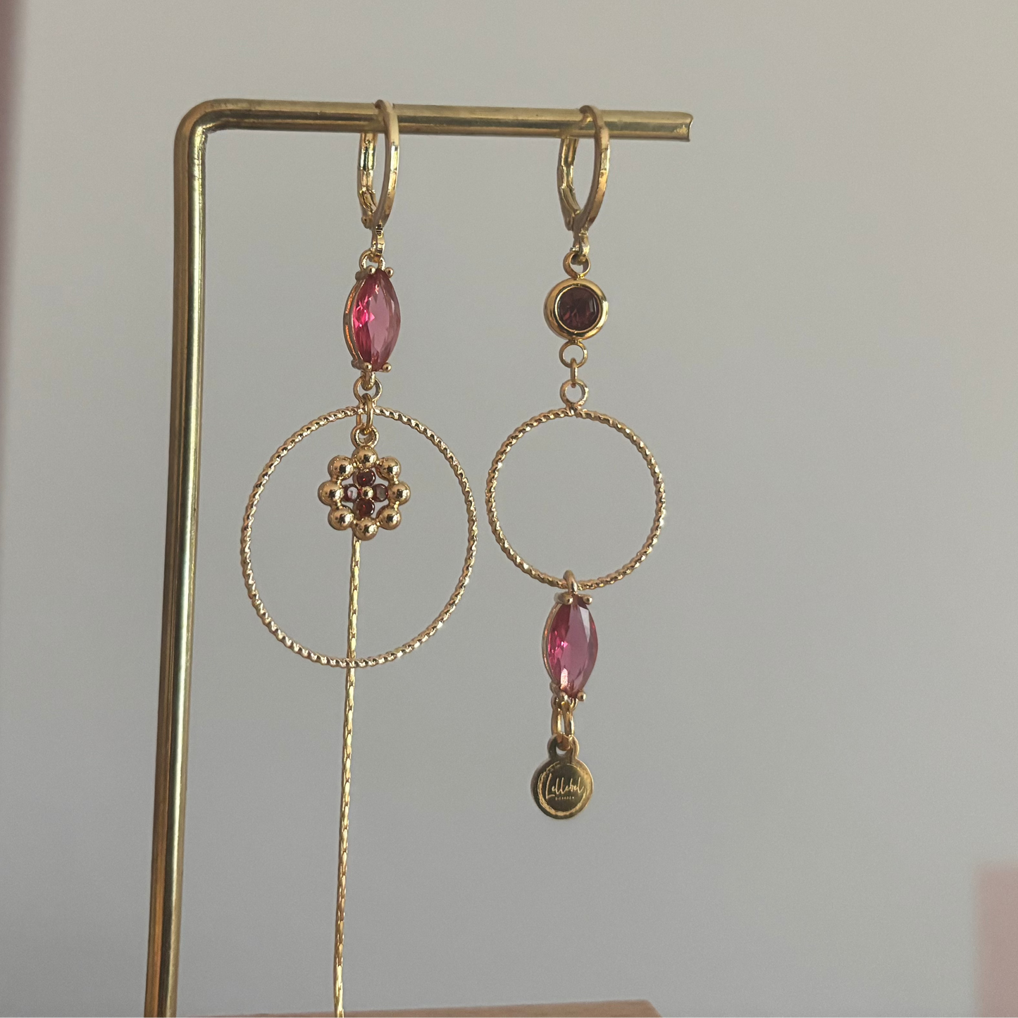 Asymmetrische 14k vergulde oorbellen Becky met magenta glasbedel, minimalistische ring, strengetje en bloemetje, circa 7 cm lang.
