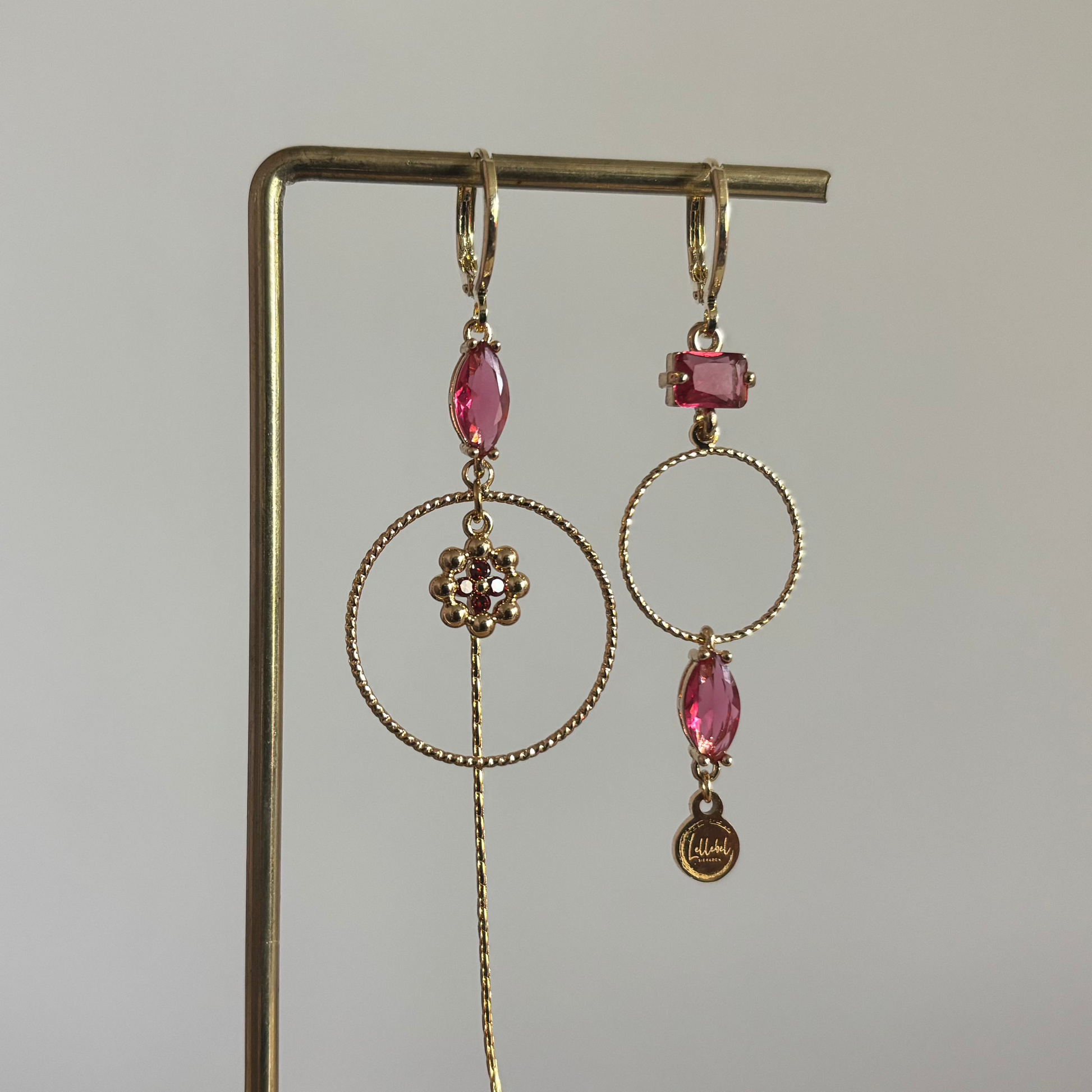 Asymmetrische 14k vergulde oorbellen Becky met magenta glasbedel, minimalistische ring, strengetje en bloemetje, circa 7 cm lang.