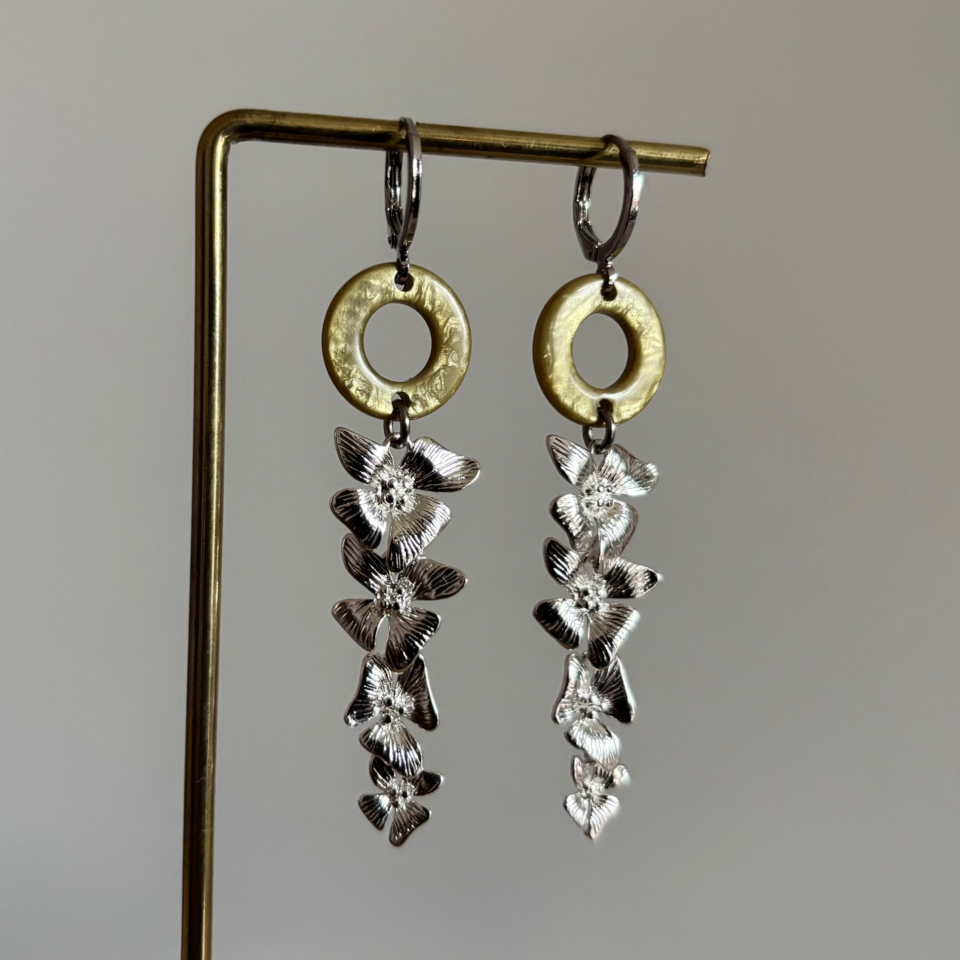 De set combineert een lichtgroen cabochon ronde ring met een hangende streng van gedetailleerde zilverkleurige bloemetjes.