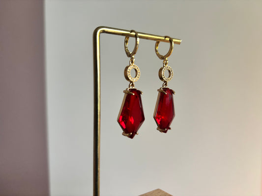 Gouden 14k vergulde oorbellen Brion met rode geometrische kristallen en kleine zirkonia details op een standaard.