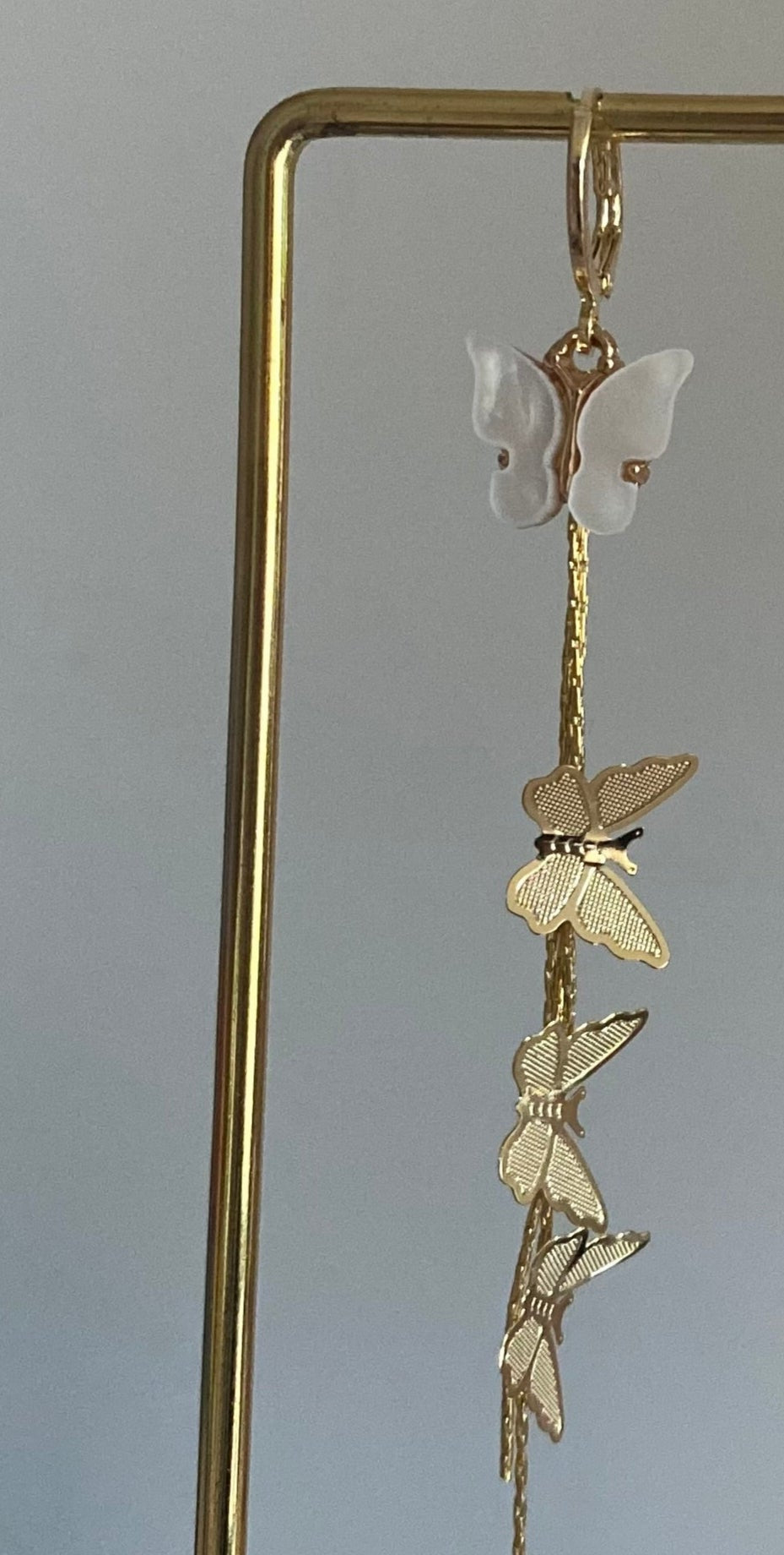 Asymmetrisch paar met 14K vergulde vlinderstreng, Shell vlinders en een mini glazen hartjesbedel, aan een 14K gouden oorringetje